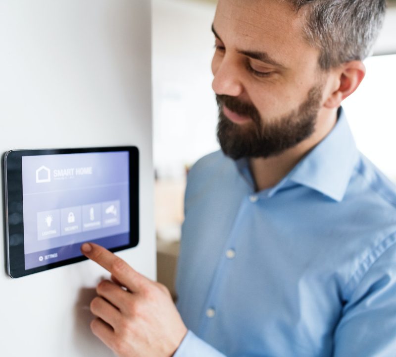 A man pointing to a tablet with smart home screen at home.