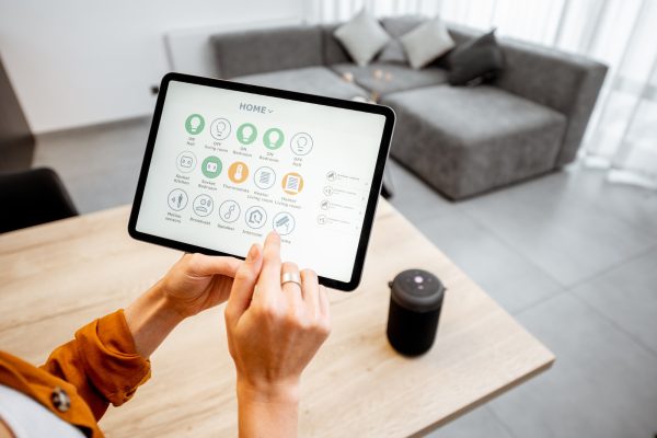 Woman controlling smart devices with a digital tablet at home